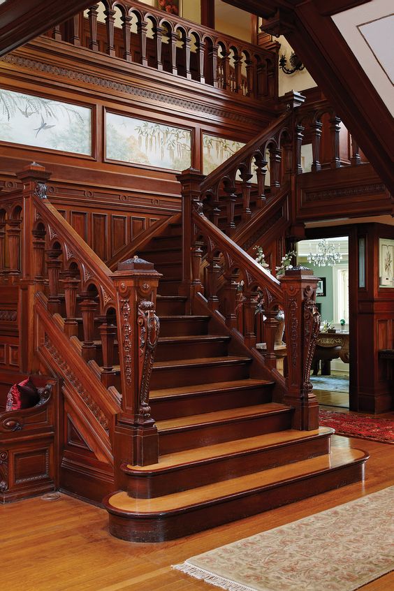 Интерьер гостиной в классическом стиле с красивой деревянной лестницей на второй этаж