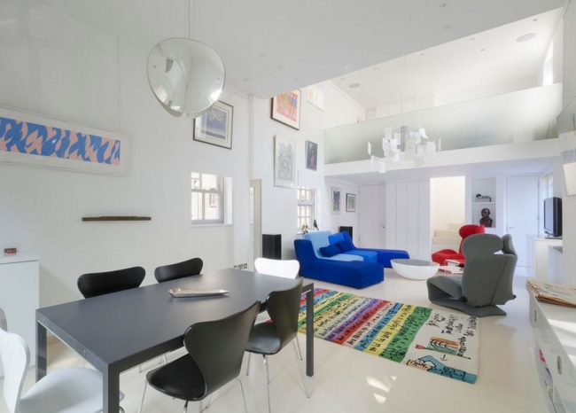 Скандинавский стиль в интерьере загородного дома: яркие детали в гостиной в скандинавском стиле: разноцветные кресла, стильный ковер и пятнистые картины