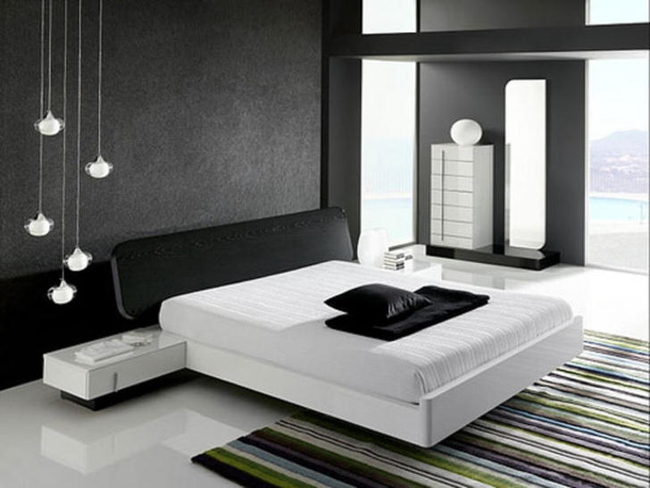 Стена у изголовья кровати, декорированная серой матовой вставкой, в соответствии со стилем хай-тек гармонирует с глянцевым белым полом.