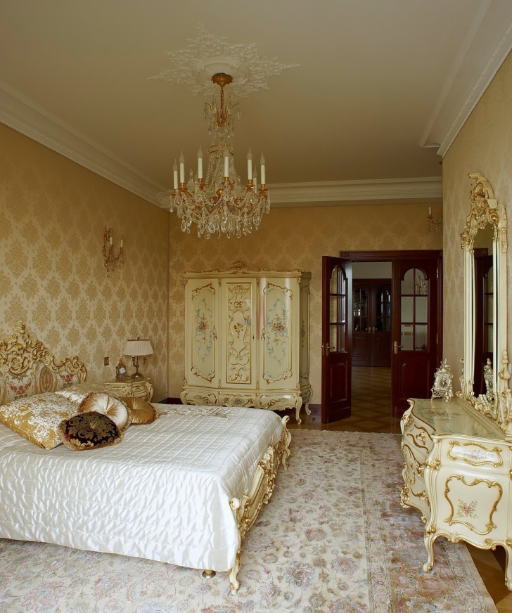 Шикарная люстра и потолок с лепниной гармонично сочетаются с деревянной мебелью в золотых тонах. 