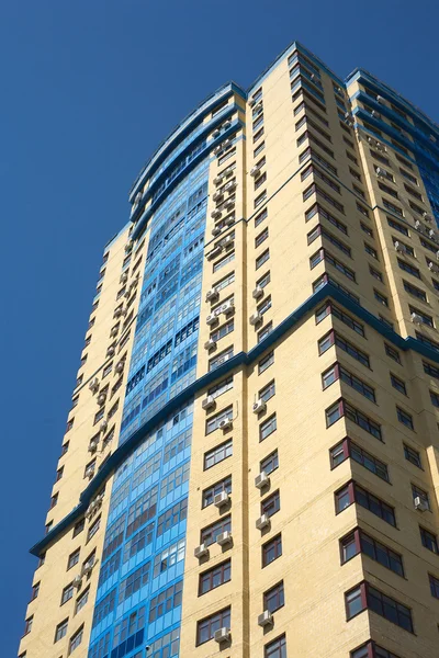 Высокий желтый современный многоэтажный на вертикальный вид голубое безоблачное небо — стоковое фото
