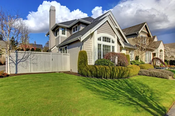 Классический американский дом с забором и зеленой травы во время весны — стоковое фото