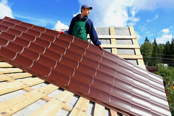Рабочий помещает металлические плитки на крышу — стоковое фото