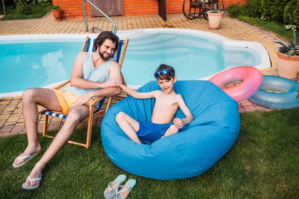 Smiling Father Son Resting Swimming Pool Backyard Summer Day — стоковое фото