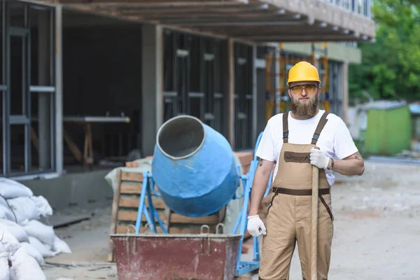 Young Builder Hardhat Protective Googles Standing Shovel Concrete Mixer Construction — стоковое фото
