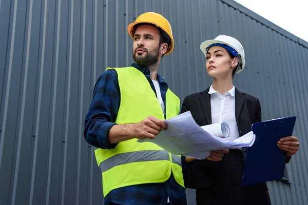 Female Engineer Male Worker Blueprints Clipboard Looking Construction — стоковое фото