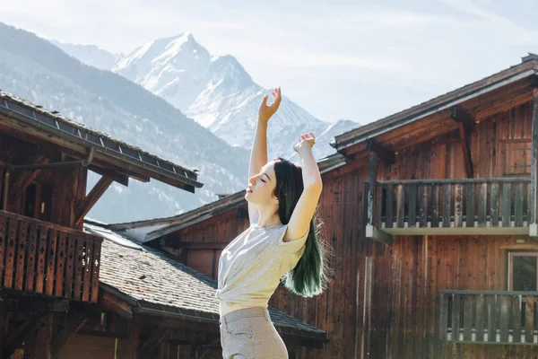 Красивая Молодая Женщина Поднимая Руки Стоя Между Деревянных Домов Горной — стоковое фото